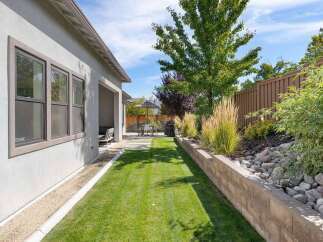 Enjoy outdoor living in this beautifully landscaped backyard, featuring a lush green lawn perfect for recreation and a covered patio area for shaded relaxation.