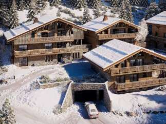 Experience luxurious mountain living in this stunning chalet nestled amidst snow-covered pine trees.
