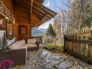 Enjoy the serene mountain views from this charming wooden cabin's covered patio.