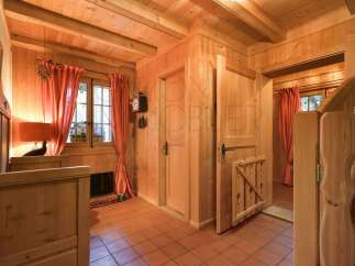 Step into a charming wooden interior featuring warm pine walls and ceilings, complemented by rustic terracotta tile flooring.