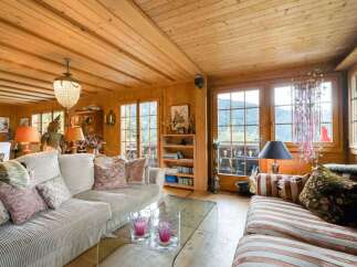 Experience rustic charm in this cozy living room, featuring warm wood paneling throughout and a stunning mountain view from the large windows.