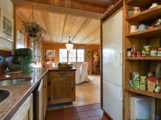 Experience rustic charm in this cozy kitchen, featuring warm wooden paneling and a granite countertop with a double sink.