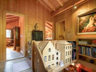 Step into a charming wooden interior featuring a dollhouse replica of a Dutch-style building, perfect for a unique display.