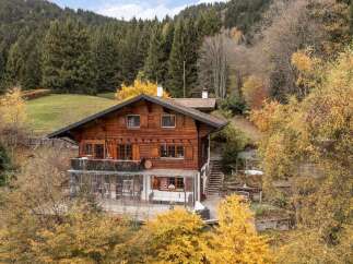 Nestled amidst a vibrant autumn forest, this charming wooden chalet offers a serene mountain retreat.