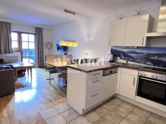 This modern apartment features a cozy living area with a comfortable sofa and armchair, perfect for relaxing after a day of skiing.