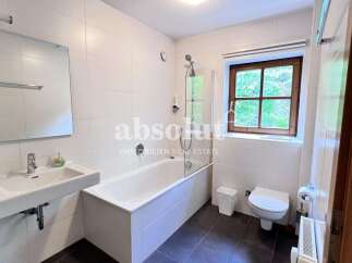 This charming bathroom features a spacious bathtub with a glass shower screen, perfect for relaxing after a long day.