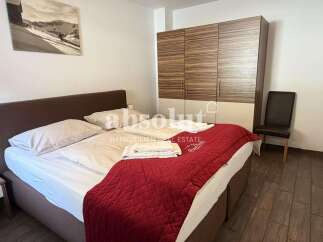 Experience comfort and style in this beautifully appointed bedroom, featuring a plush bed with crisp linens and a striking red quilted throw.