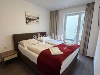 This cozy bedroom features a comfortable double bed with crisp white linens and a plush red quilted throw.