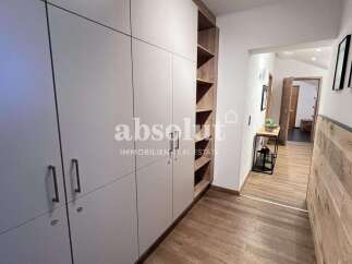 Discover this modern hallway featuring ample built-in storage with sleek, light-colored cabinetry and open shelving.