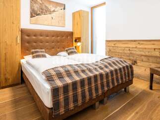 Experience alpine luxury in this beautifully appointed bedroom, featuring a plush leather headboard and a cozy plaid comforter.
