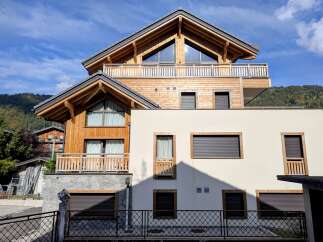 Experience modern alpine living in this stunning wooden chalet, featuring a striking A-frame design with expansive triangular windows that flood the interior with natural light.