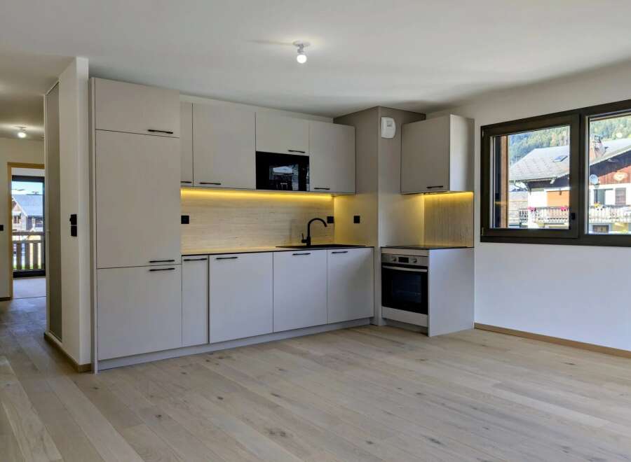 Discover this modern, light-filled kitchen featuring sleek, handleless cabinetry and integrated appliances.