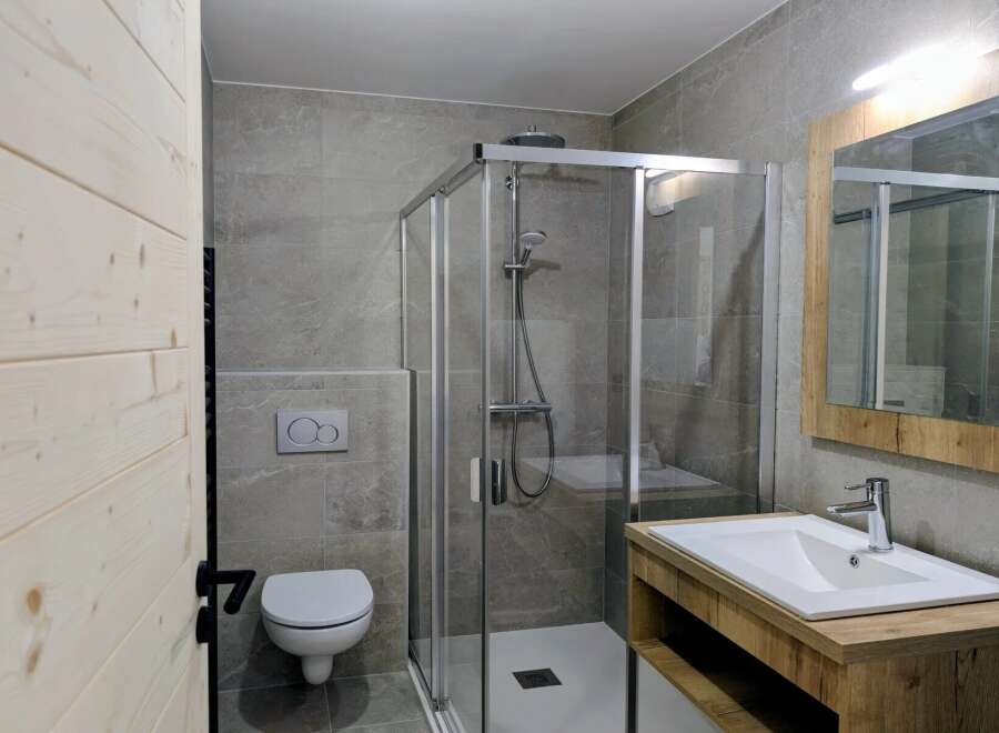 Experience modern comfort in this beautifully appointed bathroom, featuring a sleek glass-enclosed shower and a stylish vanity with a clean white sink.