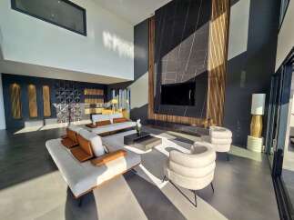 Experience modern luxury in this spacious living room, featuring a dramatic floor-to-ceiling fireplace with wood accents and a sleek entertainment center.