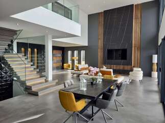 Experience modern luxury in this spacious open-concept living and dining area, featuring a dramatic two-story staircase with glass railings and integrated lighting.