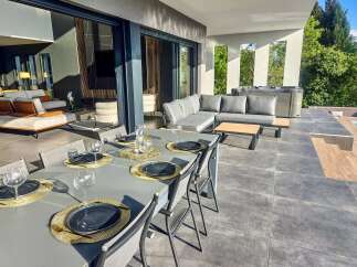 Experience luxury outdoor living with this stunning patio featuring a spacious dining area set for six, complete with elegant place settings and glassware.
