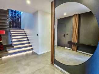 Experience modern luxury in this stunning entryway featuring a floating staircase with integrated LED lighting and a striking geometric accent wall.