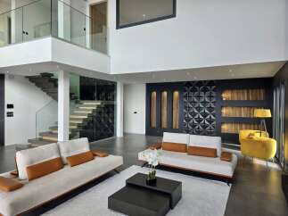 Experience modern luxury in this stunning multi-level living space, featuring a floating staircase with glass railings and a dramatic geometric accent wall.