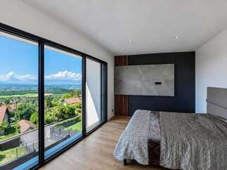 Experience breathtaking panoramic views from this modern bedroom, featuring expansive floor-to-ceiling windows that showcase a stunning landscape.