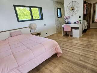 This modern bedroom features a plush pink comforter on a queen-sized bed, complemented by a stylish wooden headboard and a unique fluffy bedside lamp.