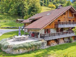 Experience rustic charm in this stunning mountain chalet, featuring a stone and wood facade, multiple balconies, and a spacious wooden deck perfect for outdoor entertaining.