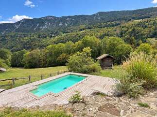 Escape to this serene mountain retreat featuring a sparkling swimming pool surrounded by a spacious wooden deck.