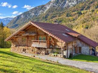 Experience the charm of this rustic wooden chalet nestled against a majestic mountain backdrop.
