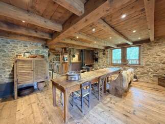Experience rustic charm in this beautifully appointed dining area, featuring exposed wooden beams and a stone wall.