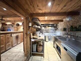 Experience rustic charm in this beautifully appointed kitchen, featuring exposed wooden beams and stone walls that evoke a sense of timeless elegance.