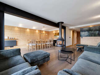 Experience modern alpine living in this stunning open-plan living and dining area, featuring a striking suspended fireplace and a large wall-mounted television.