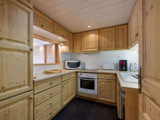 This charming kitchen features warm, natural wood cabinetry and a pass-through window, creating a cozy and inviting atmosphere.