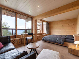 Experience breathtaking mountain views from this beautifully appointed bedroom, featuring a cozy seating area and a comfortable bed.