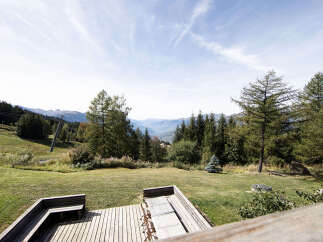 Enjoy breathtaking mountain views from this stunning property's expansive wooden deck.