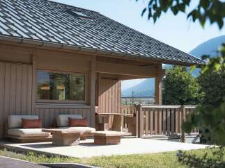 Experience serene mountain living in this charming wooden cabin, featuring a spacious deck with comfortable seating and rustic wooden furniture.