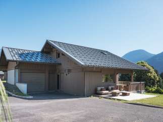 Experience modern mountain living in this stunning wooden chalet, featuring a sleek metal roof and expansive windows that invite natural light.