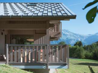 Experience breathtaking mountain views from this stunning wooden chalet, featuring a durable metal roof and expansive balconies perfect for outdoor relaxation.