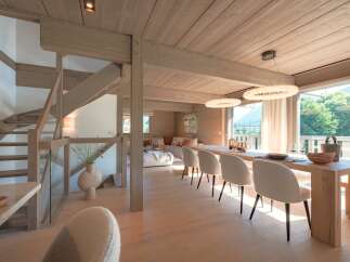 Experience luxurious living in this modern chalet, featuring a stunning open-plan dining and living area with a large wooden dining table and plush seating.