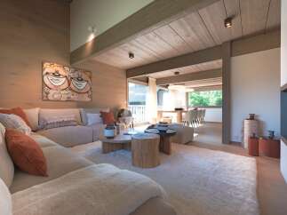 Experience luxurious mountain living in this stunning chalet, featuring a spacious open-plan living area with a plush sectional sofa and a cozy sheepskin rug.