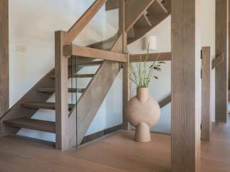 Experience modern living with this stunning staircase featuring a sleek glass railing and warm wooden accents.