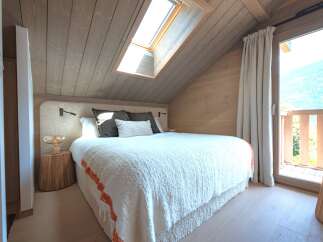 Experience cozy mountain living in this charming bedroom featuring a plush bed with a textured throw and a unique tree-stump nightstand.