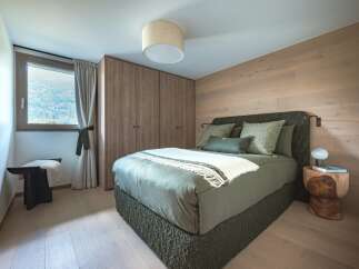Experience serene mountain living in this beautifully appointed bedroom, featuring a plush green bed adorned with textured pillows and a cozy throw.