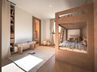 This charming children's bedroom features a cozy wooden bunk bed with plaid bedding, perfect for sleepovers.