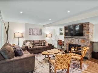 Cozy up by the stone fireplace in this inviting living room, featuring comfortable seating and a large flat-screen TV.
