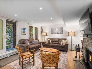 Cozy living room featuring plush brown sofas and rustic wooden chairs, perfect for relaxation.