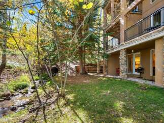 Enjoy the serene beauty of autumn from this property, featuring a charming stream and lush trees with vibrant fall foliage.