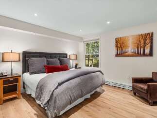 Experience ultimate comfort in this beautifully appointed bedroom, featuring a plush king-size bed with luxurious grey linens and a striking red accent pillow.