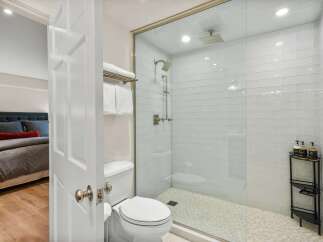 Step into a beautifully appointed bathroom featuring a spacious glass-enclosed shower with modern subway tile and a dual showerhead system.
