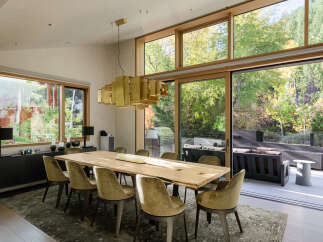 Experience luxurious indoor-outdoor living in this stunning dining room, featuring a large live-edge wood table and plush velvet chairs.
