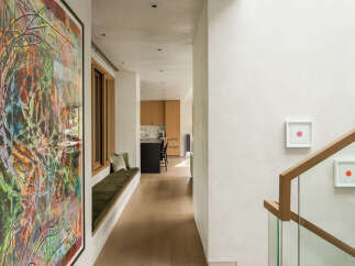 Experience modern luxury in this stunning hallway, featuring a vibrant abstract art piece and a built-in bench with plush cushions.