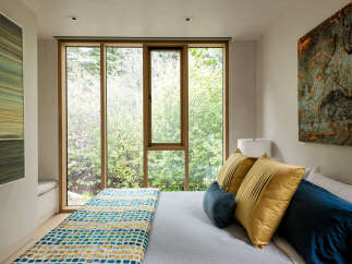Experience serene living in this bedroom, featuring a large window that floods the space with natural light and offers stunning views of the surrounding greenery.